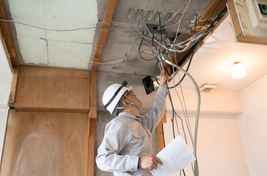 マンション・スクケルトンリフォーム・電気工事・図面を持ちながらチェックする作業員